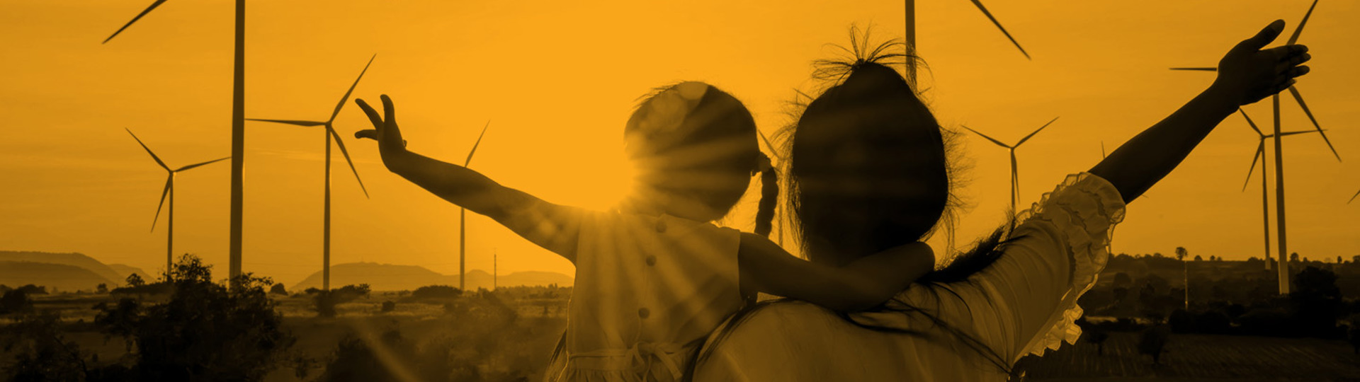 Silhouette of an adult and a child against a backdrop of a landscape with wind turbines
